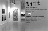 A photograph of a gallery space.  The right half of the image is taken up by a wall with printed text identifying the exhibitions, 