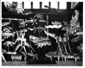 A black and white photograph of various floating constructed fish-like objects in space.