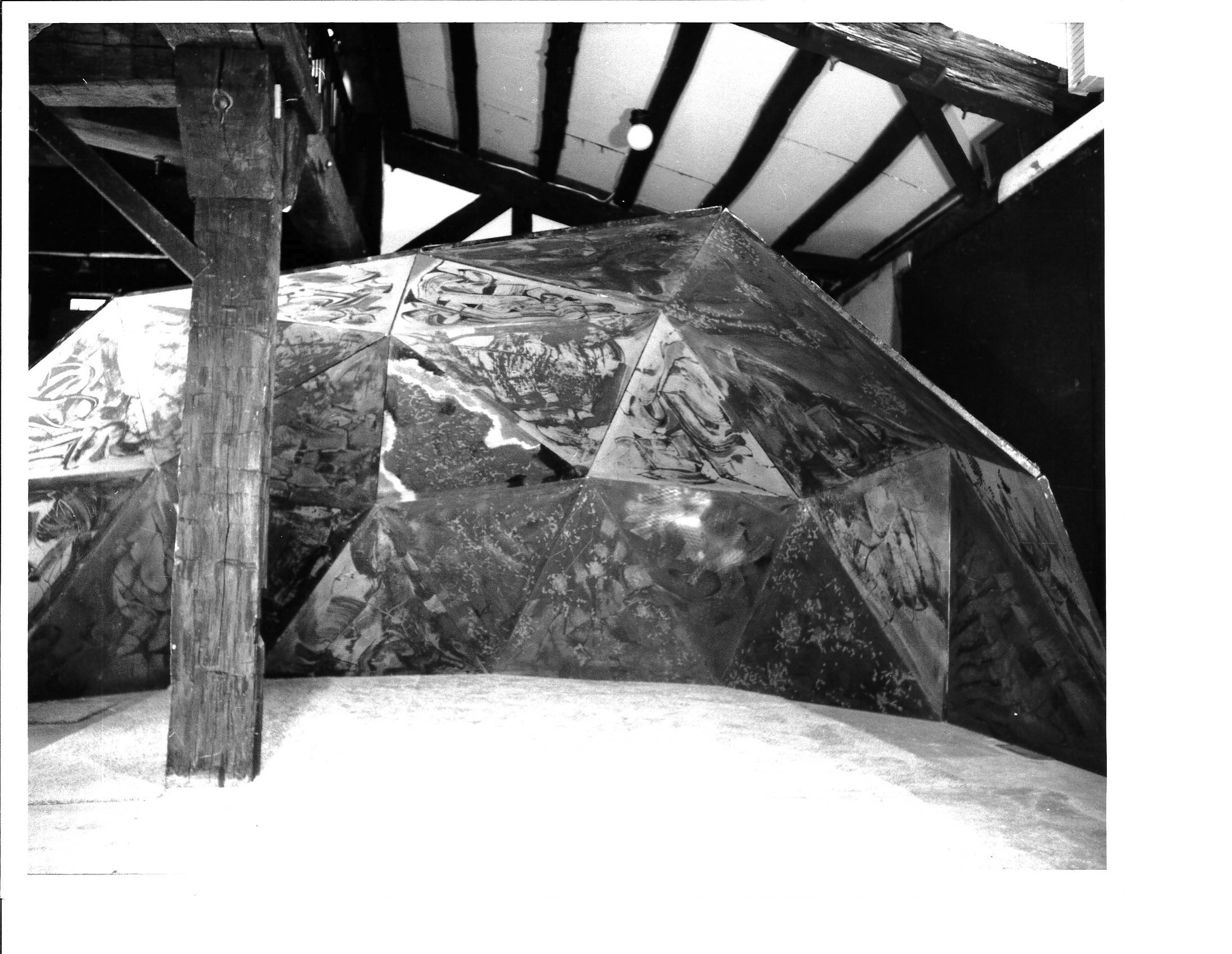 A black and white photograph of a large constructed rock dome in a galelry space.