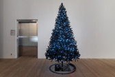 A black Christmas tree stands in the room, adorned with white twinkling lights. A black toy train circulates around the shiny black base of the tree.