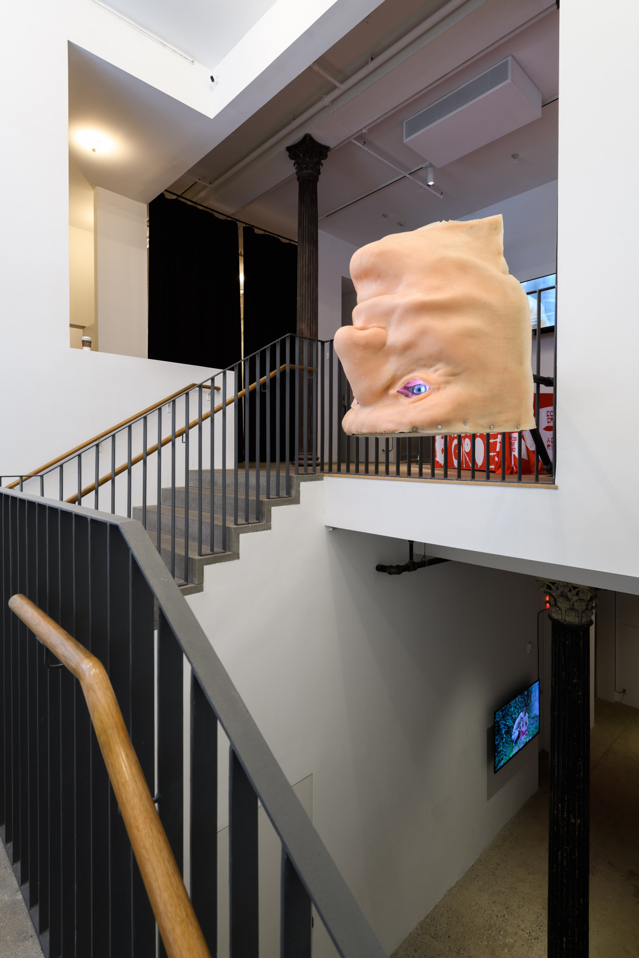 An image of an exhibition space with a sculpted, larger than life head that hangs in the mezzanine.