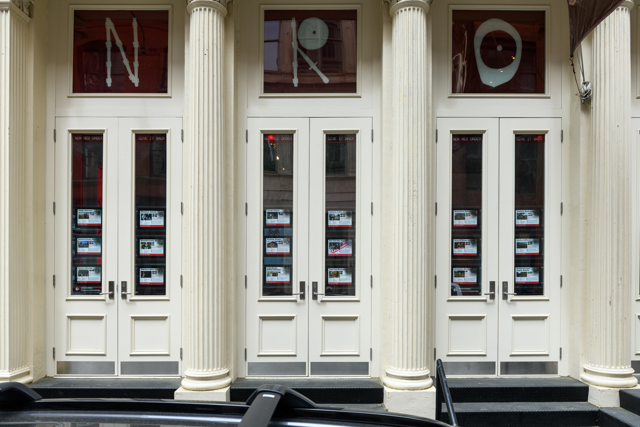 An image of a white facade with real estate listings in the windows, and above them, in vinyl lettering reads 