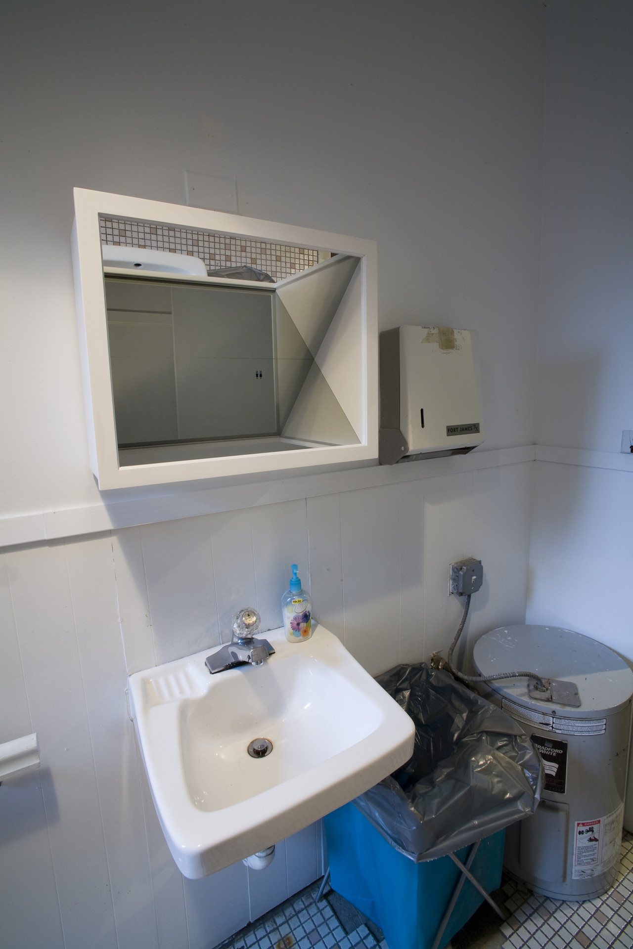 The corner of a small white room features elements implying that it