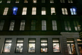 The exterior of a Soho building at night. Inside the third floor are two glowing blue neon quotation marks visible from outside.