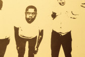 A yellow print of a person with glasses leaning over and looking forward. Next to him is another person, his hands holding his chest, looking down.