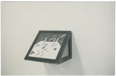 A rectangular, abstract painting is mounted on a black frame at an angle to the white gallery wall.