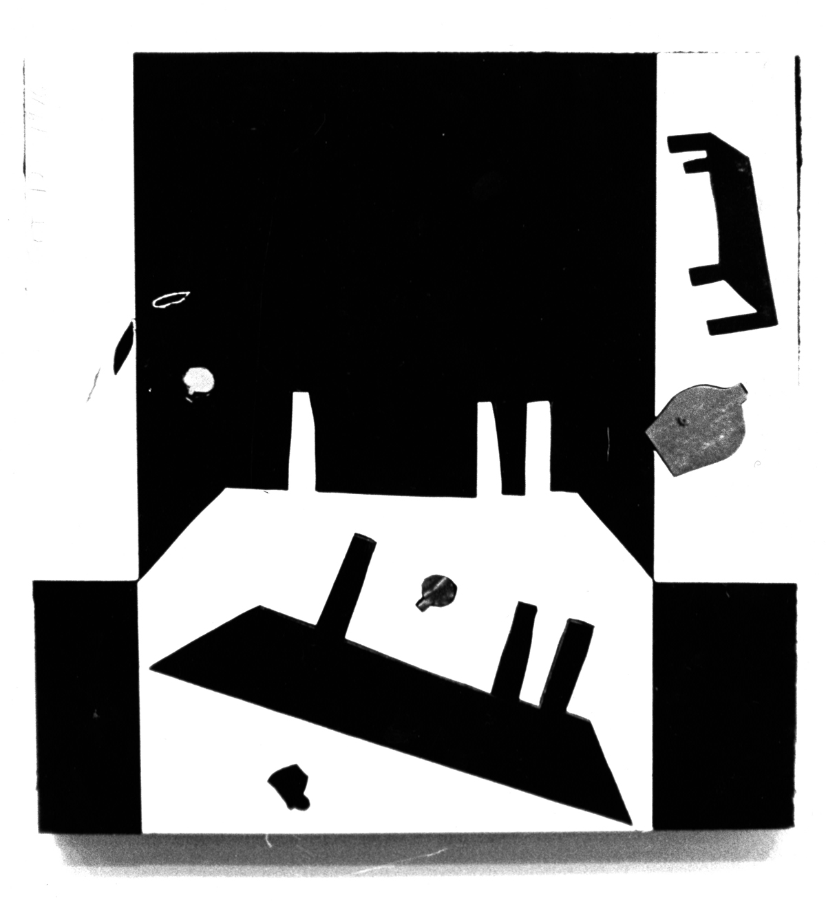 A photograph of a rectangular, abstract black-and-white work mounted on a white wall. The pattern resembles a geometric face on a checkerboard.