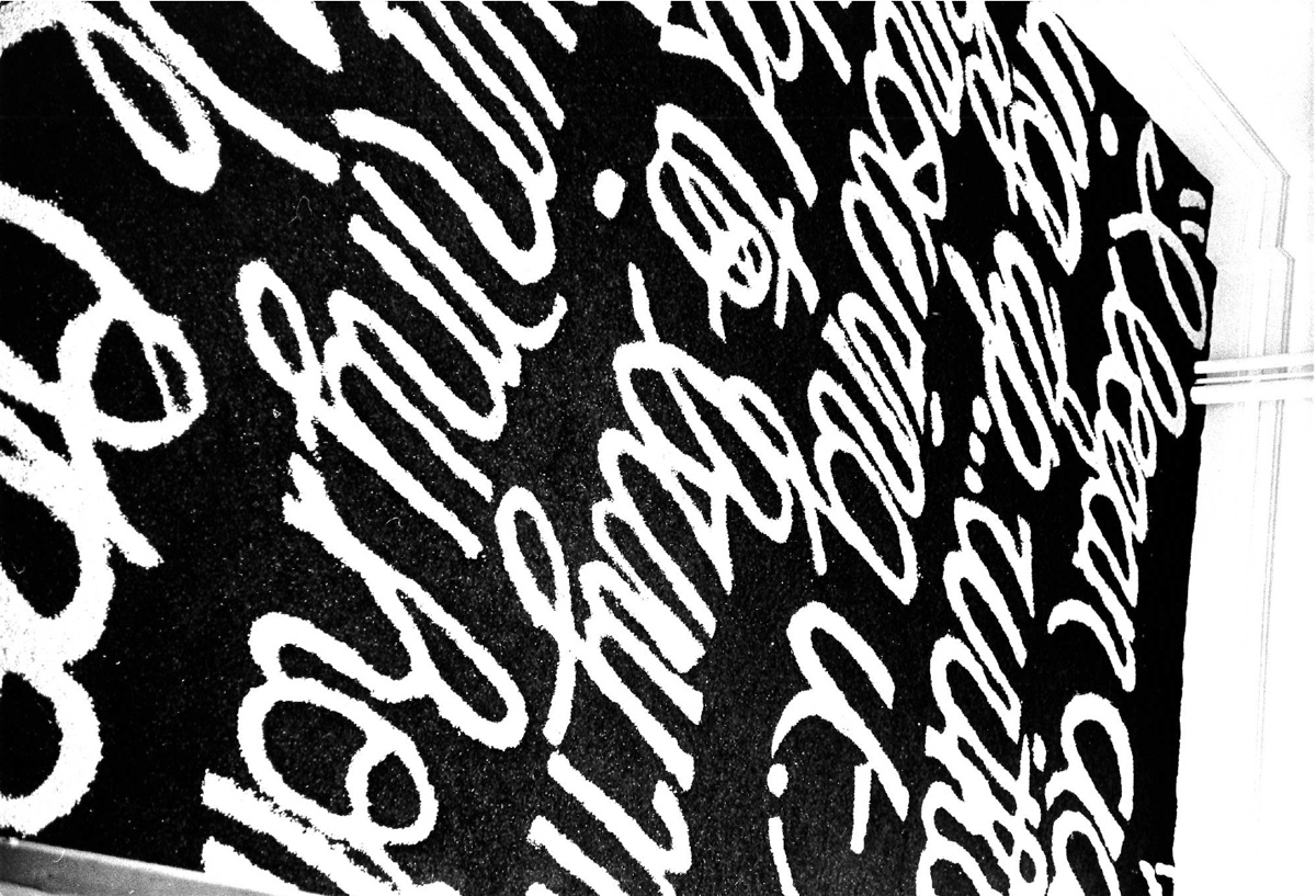 Black and white photograph of cursive white text on a black background on the floor.