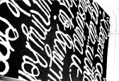 Black and white photograph of cursive white text on a black background on the floor.