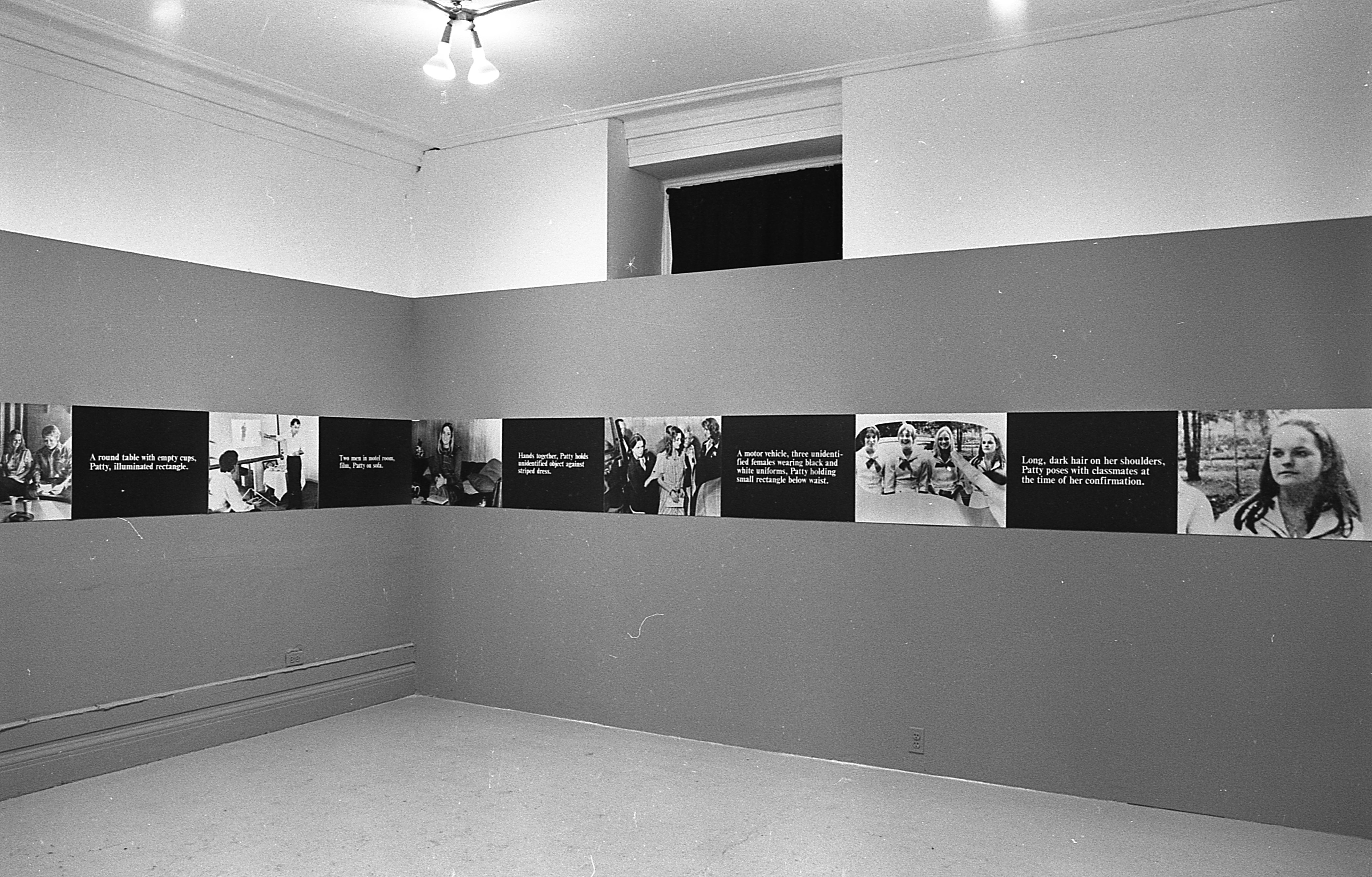 A continuous strip extends around the perimeter of the room, hung up on the walls. The strip alternates between photographic stills and black boxes overlaid with white text.