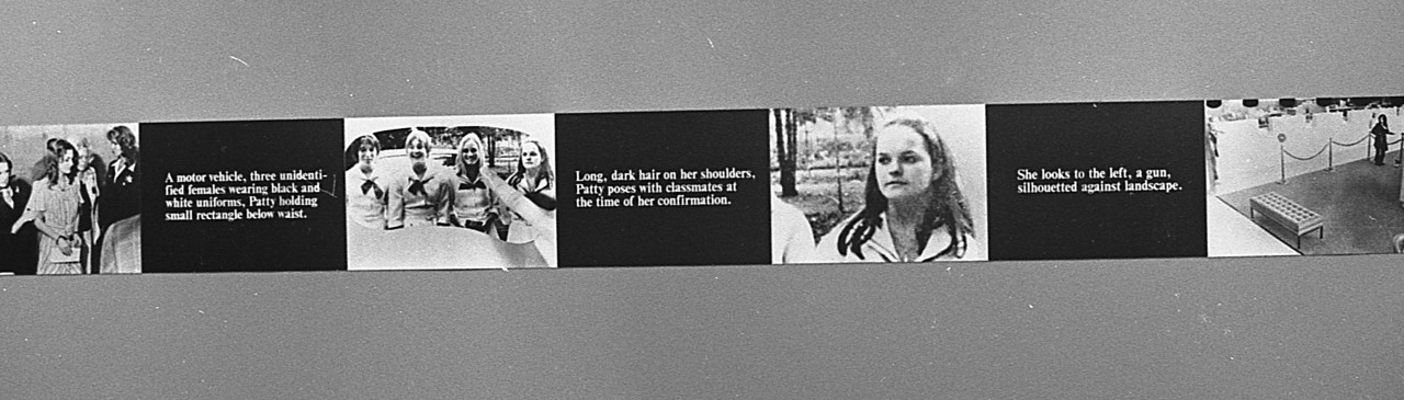 A continuous strip extends around the perimeter of the room, hung up on the walls. The strip alternates between photographic stills and black boxes overlaid with white text.