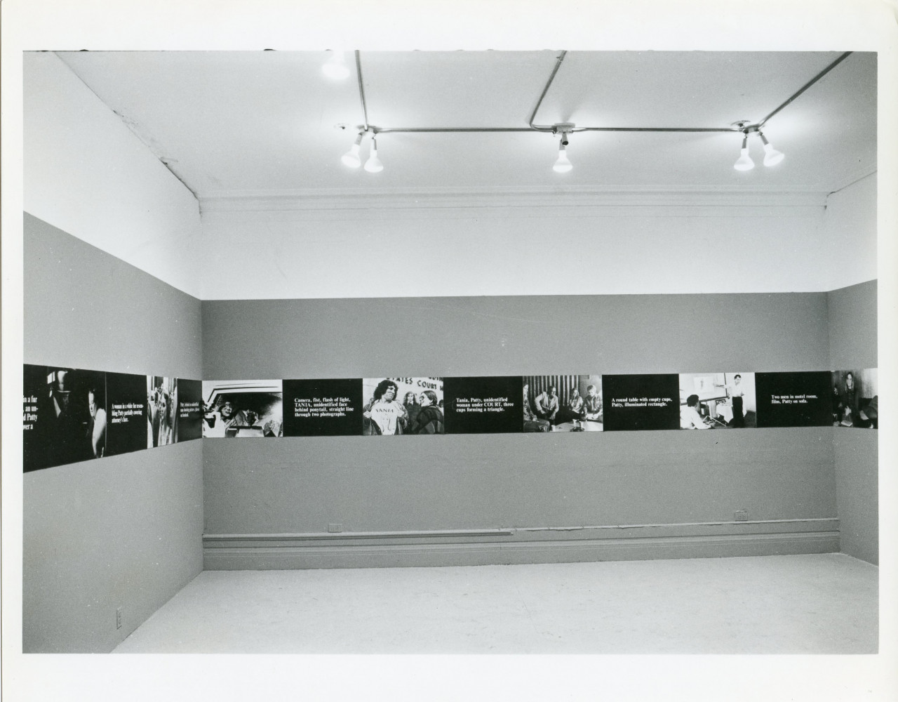 A continuous strip extends around the perimeter of the room, hung up on the walls. The strip alternates between photographic stills and black boxes overlaid with white text.
