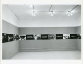 A continuous strip extends around the perimeter of the room, hung up on the walls. The strip alternates between photographic stills and black boxes overlaid with white text.