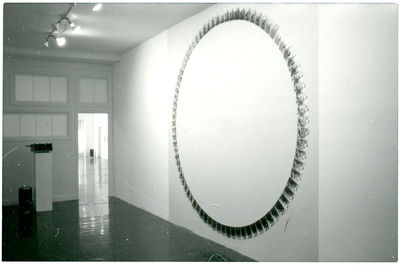 A gallery space with a large circle of decals on the wall on the right. In the far left corner, a projector sits on a pedestal.