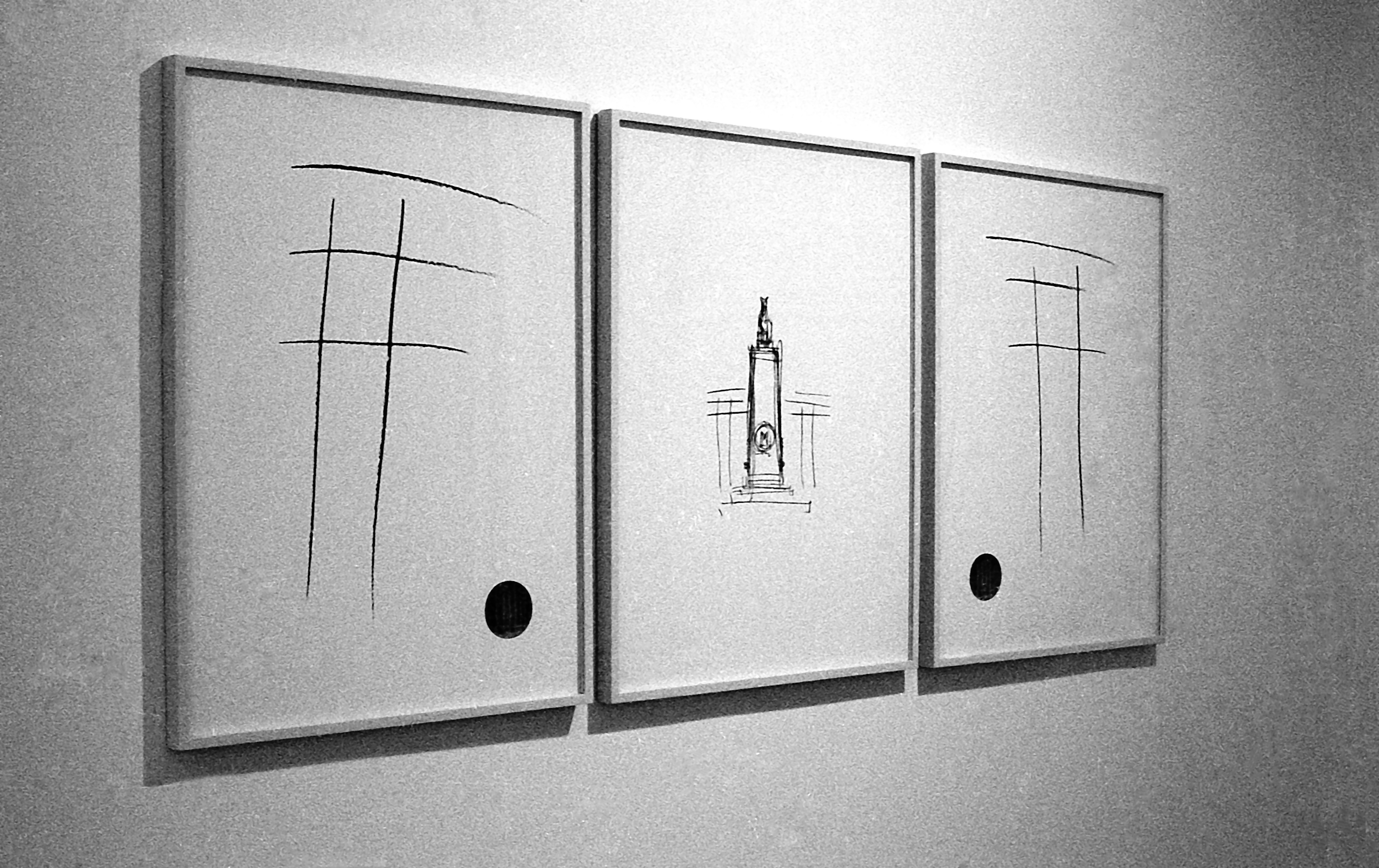A black and white installation photograph of three framed drawings on a white wall. The center frame is a pared down sketch of a column, and the flanking frames feature feature a simple croshatch of four lines, topped with a fifth.