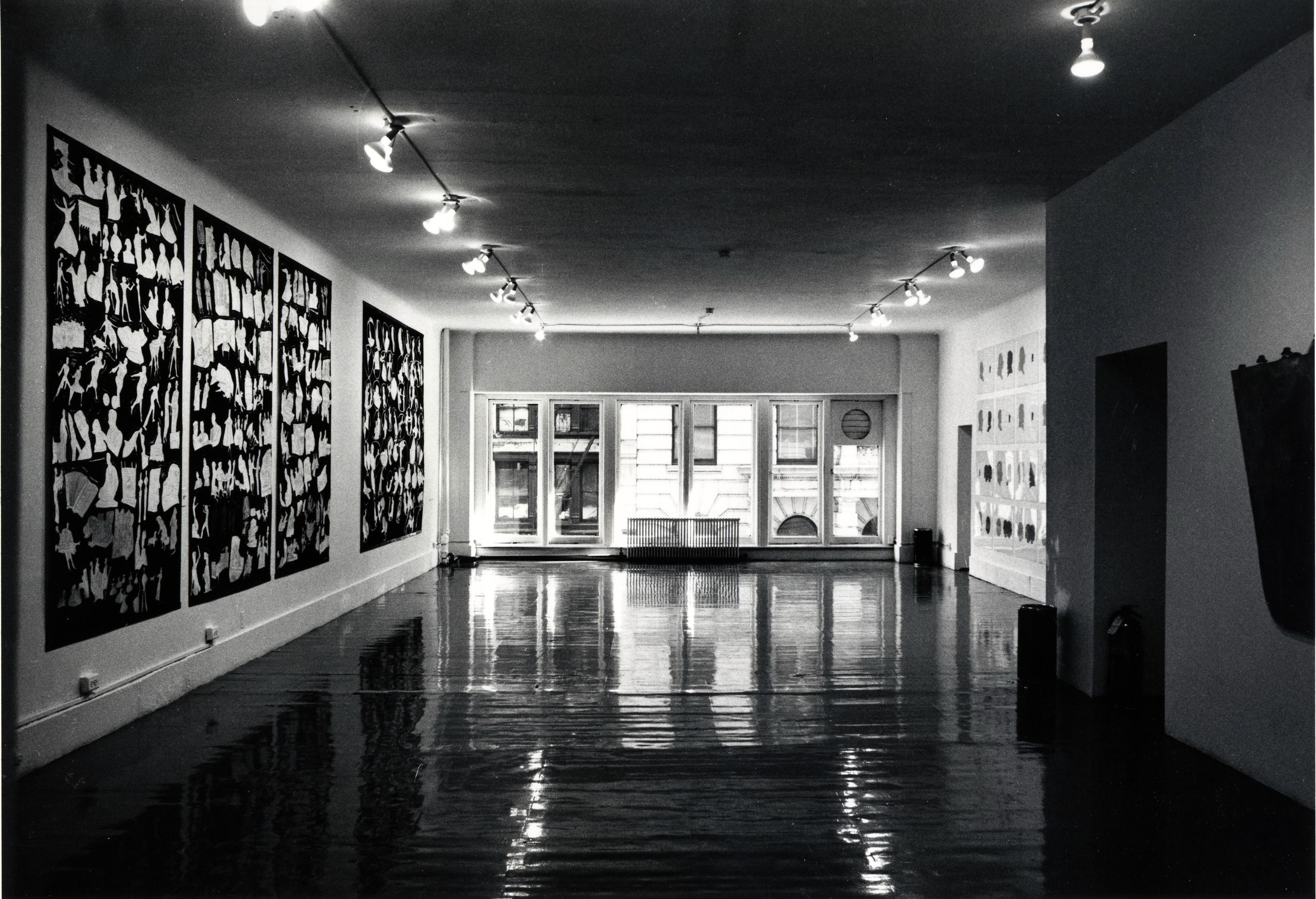 [Artworks hang on walls on the left and right. In the background, a neighboring building is visible through the window.]