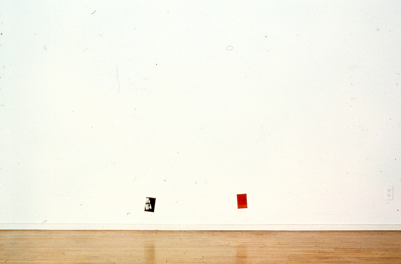 Two photographs are mounted on a white gallery wall.