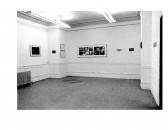 Frame photographs and text hang on the wall in a gallery space.