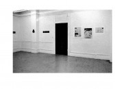 Frame photographs and text hang on the wall in a gallery space.