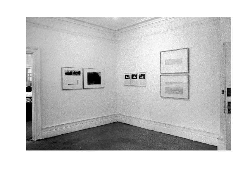 Frame photographs and text hang on the wall in a gallery space.