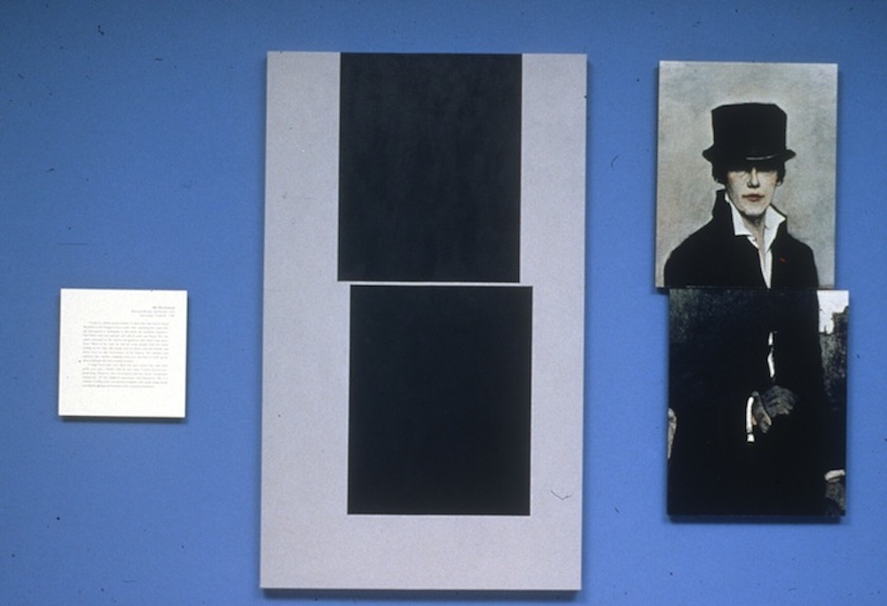 A small square of illegible text, an abstract image of two black squares on grey, and a painting of a person in period dress and a top hat all hang on a blue wall.