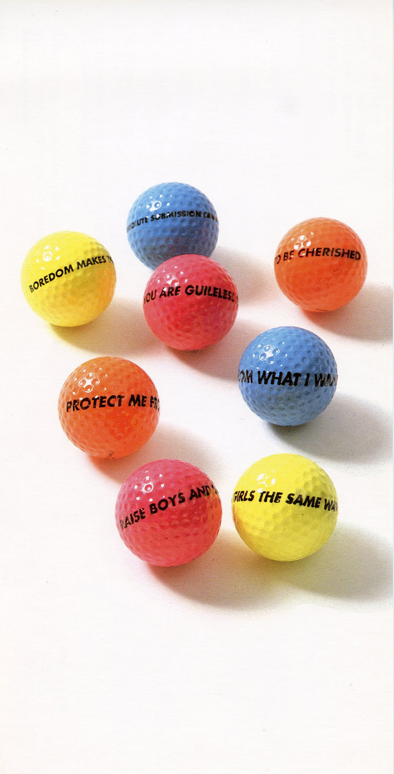 Eight vibrantly colored blue, pink, yellow, and orange golf balls rest on a white backdrop. Various statements written in black capitalized text adorn each gold ball, including phrases such as, "PROTECT ME FROM WHAT I WANT" and "RAISE BOYS AND GIRLS THE SAME WAY."