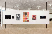 Six artworks are mounted to a white gallery wall. On the far left and right are three black and white compositions, followed by a photograph of the back of a walking figure. At the center are two colorful, abstract compositions on paper.