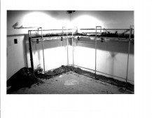 Dirt appears on the edges of the floor and in the plastic clear cases hanging above them in a gallery setting.