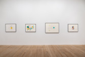 A color image of four framed works displayed against a white wall. The drawings depict abstract compositions made up of colorful shapes and lines, and pencil strokes.