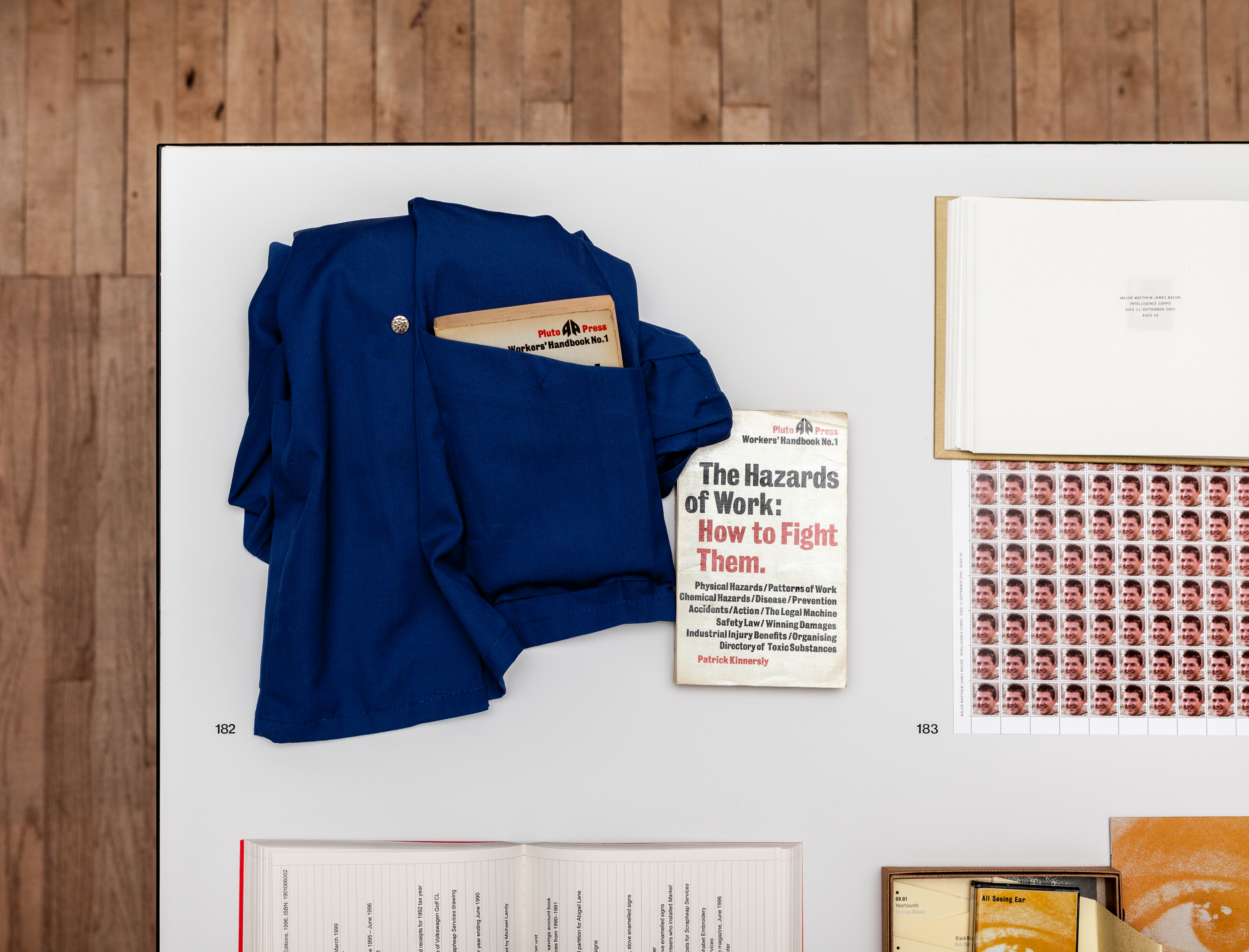 A blue shirt sits folded on a table with a book inside its pocket. Next to it, a book with text on the cover that reads, 