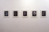 Five photographic collages installed in white frames arranged in a horizontal row along a blank wall.