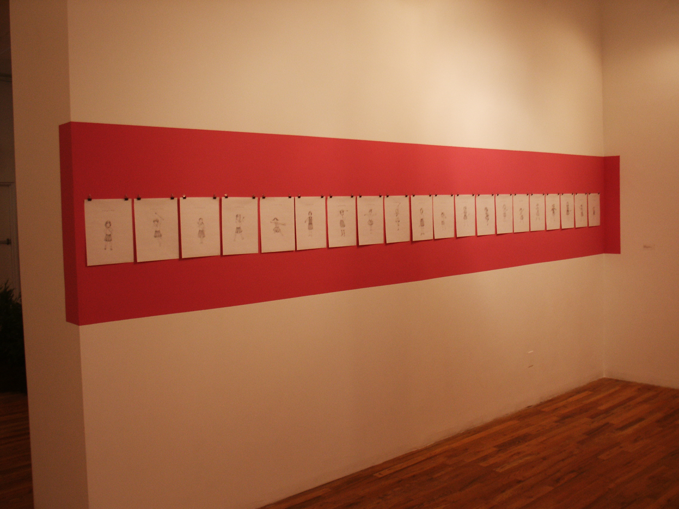 A red stripe is painted on a white wall. Hung in the red stripe are twenty sheets of white paper with a single figure drawn on each one.
