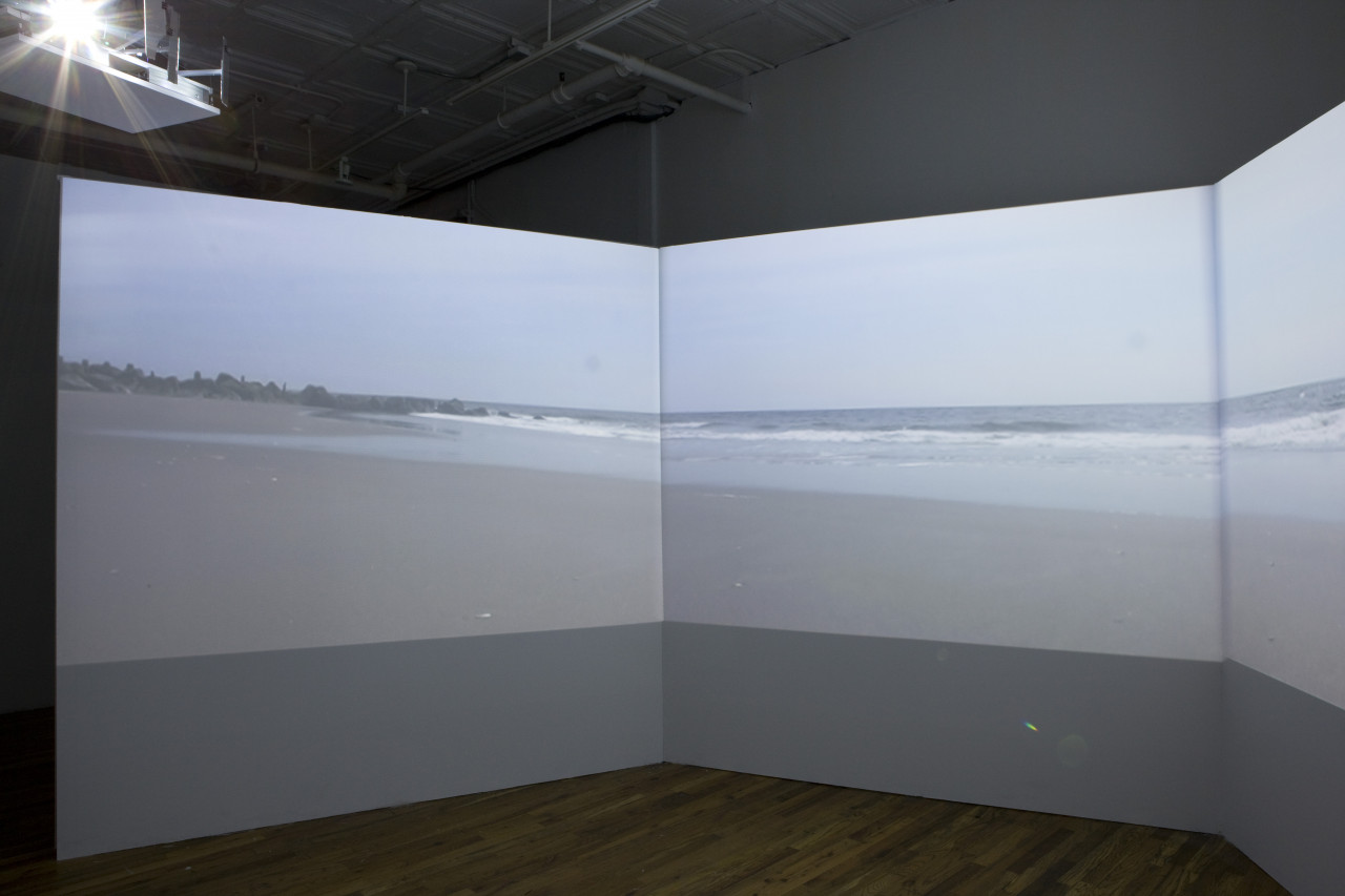 An image of a shoreline is projected on a trifold screen.
