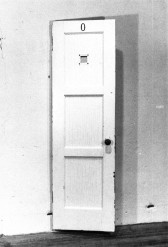 A narrow, white door with the number 