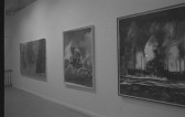 A photograph of three paintings hanging in a row on a white gallery wall.  The closest to the camera, on the right, shows a ship at sea, the center shows a fountain, and the painting on the left is an abstract composition of black diagonal lines.