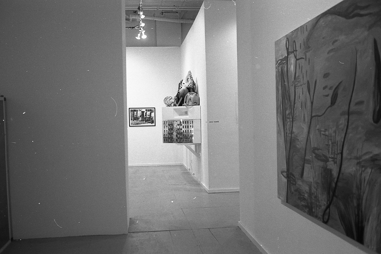 A photograph of a large painting of vines and water hanging on a white gallery wall.  Beyond it, more painting and sculptures are visible in an adjacent gallery.