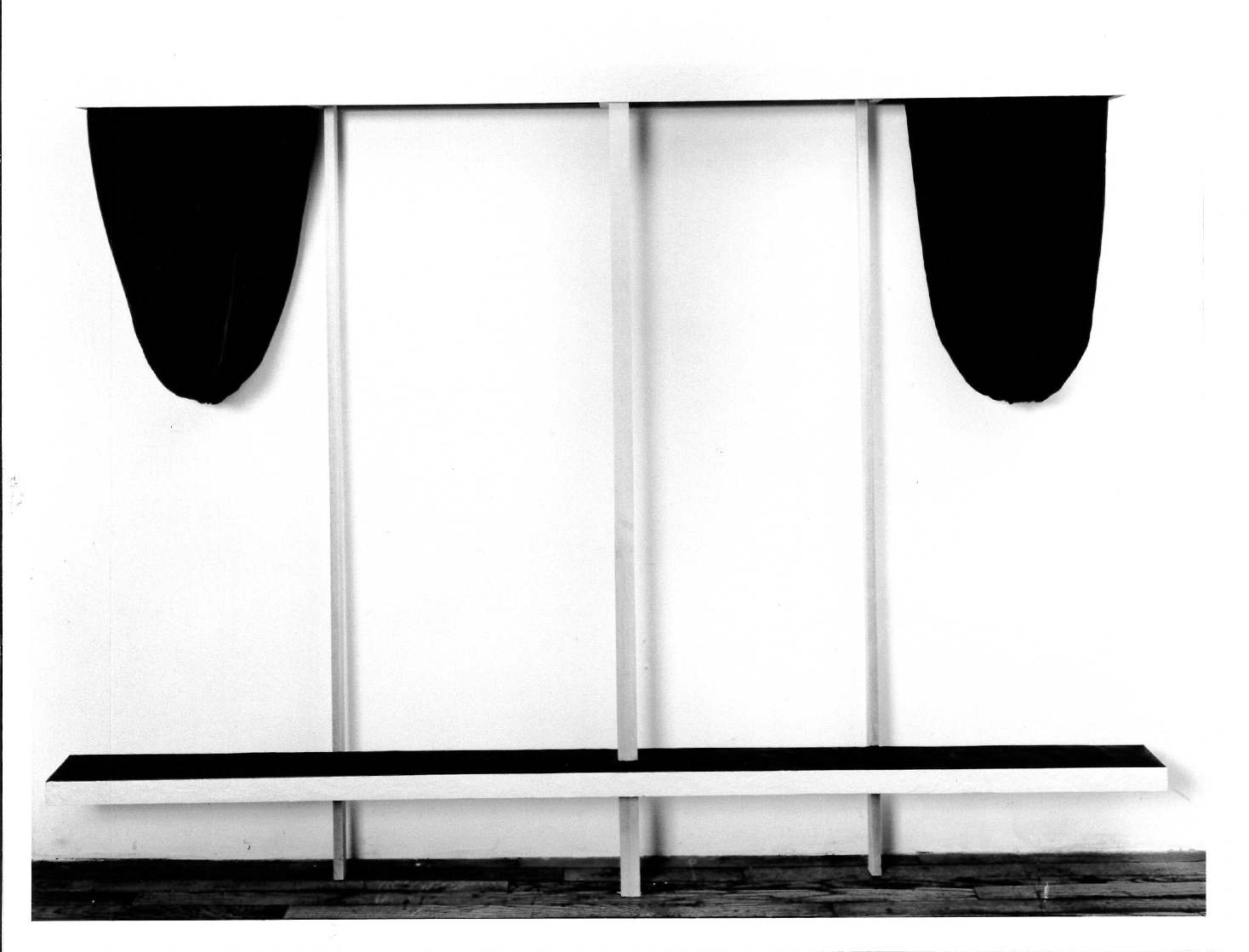 A black and white image of a black bench with two distinct black drapery on both sides behind it.
