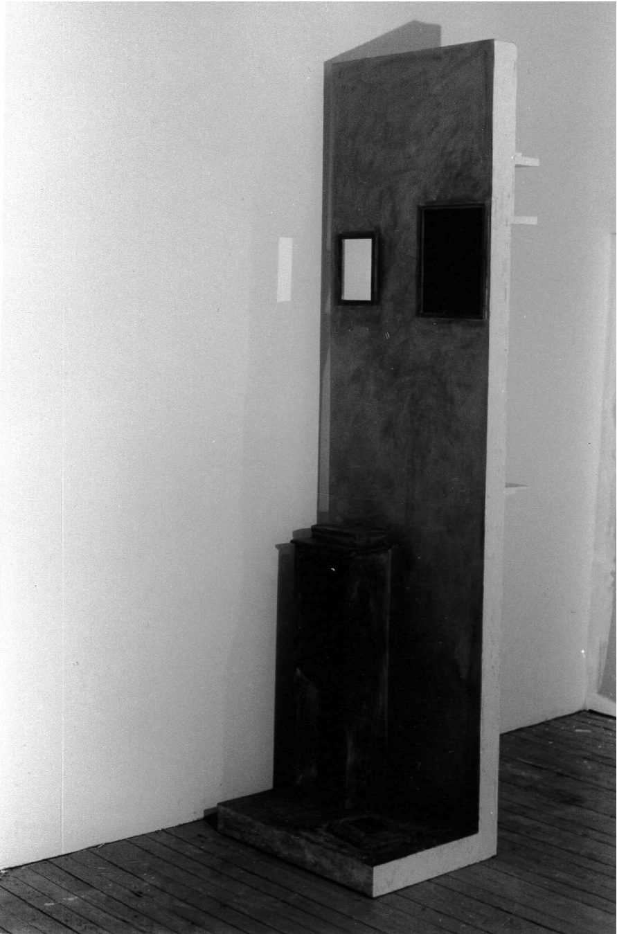 Dark photograph of a plywood sculpture in a gallery space.