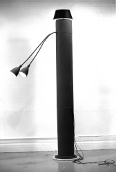 A black-and-white photograph of a long floor lamp with two protruding lampshades.