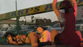 Two images are superimposed over each other. The background image features car lot with a sign reading 