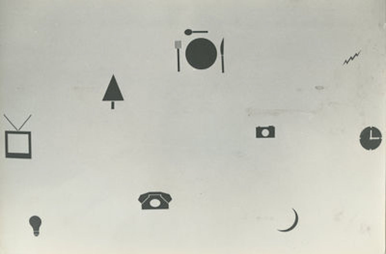 A black and white photograph of dark silhouetted shapes pasted on a wall, including a tree, a television set, a phone, a lightbulb, and a place setting.