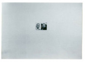 A black and white photograph of a small photograph against a white surface. The image pictured features the faces of two figures.