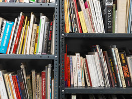 Staggered metal shelves that are filled with books of various color and sizes.