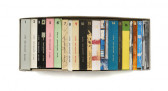 Books, with series numbers (1-20) marked at the top of the spine, rest on an encolsed shelf against a white wall.