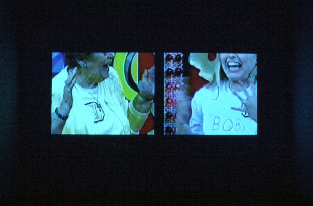 A split screen of two people, each visible between their nose and their chest. Both are extremely excited, with their hands raised up.