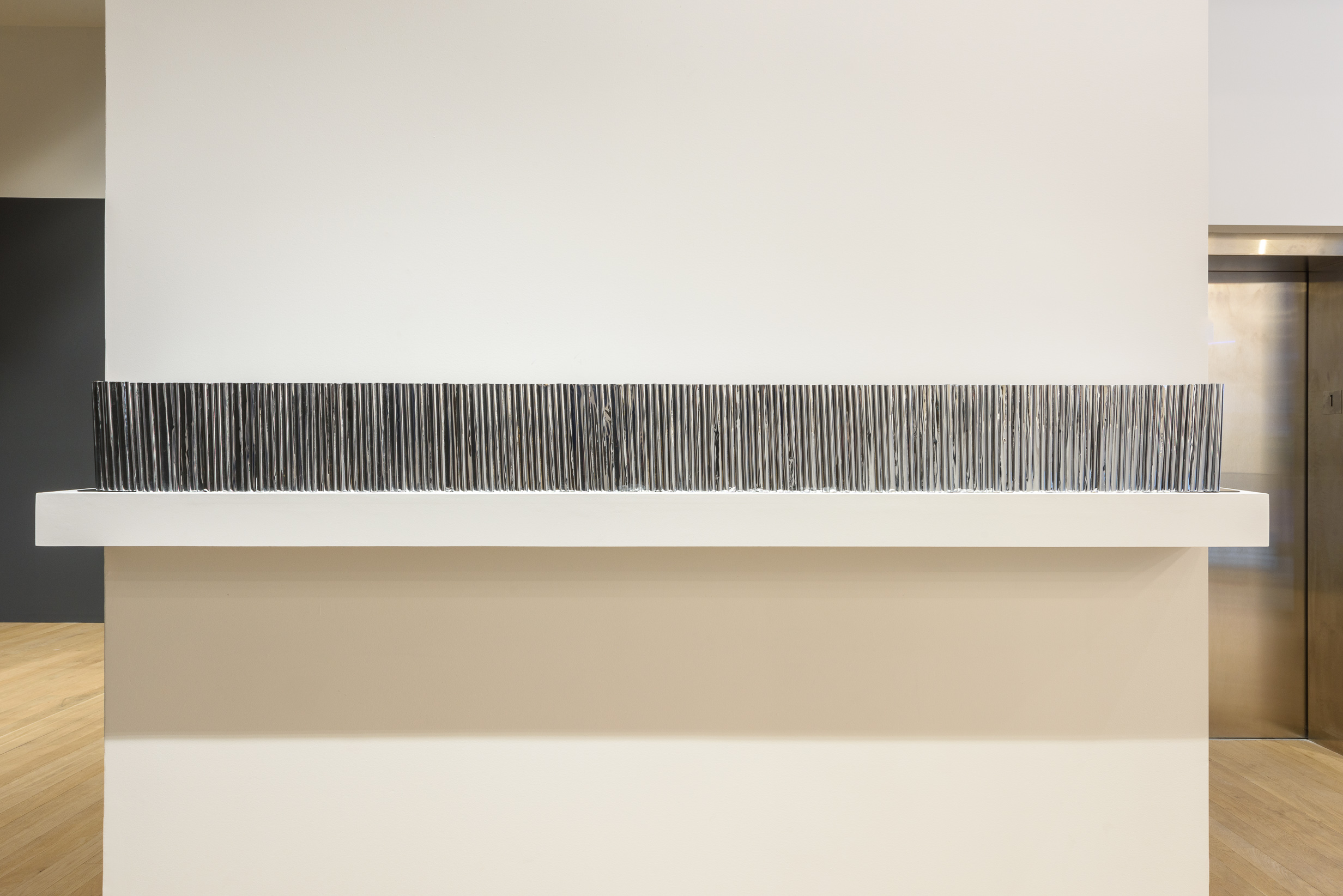 A photograph of a bookshelf lined with books covered in silver mylar.