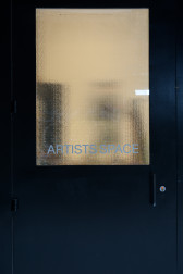 A view of the door to Artists Space from outside. The glass in the door is foggy; inside, a few dark shapes are visible.