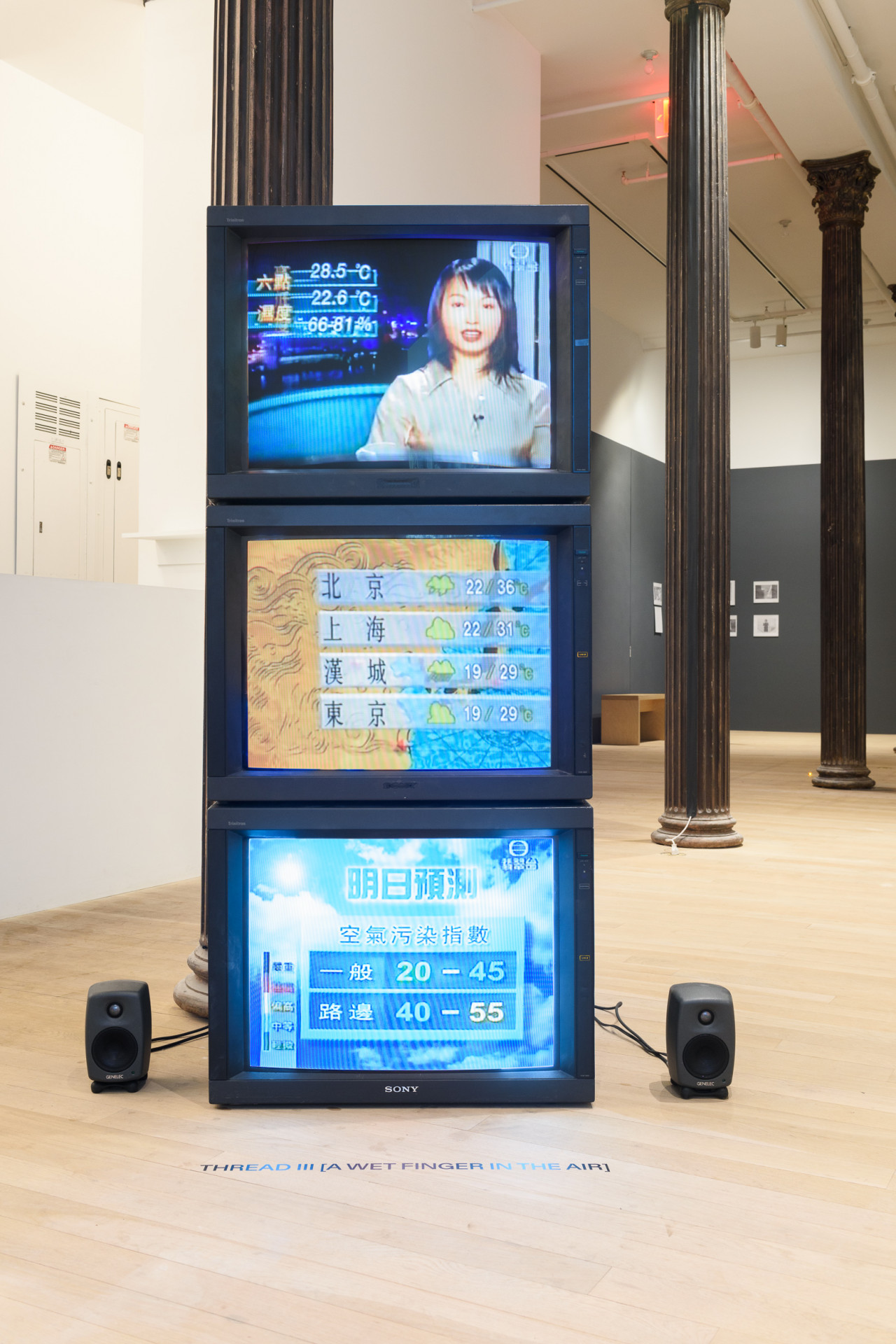 A photograph of three TV screens stacked on top of each other. Two small speakers are visible on either side of the TV screens.