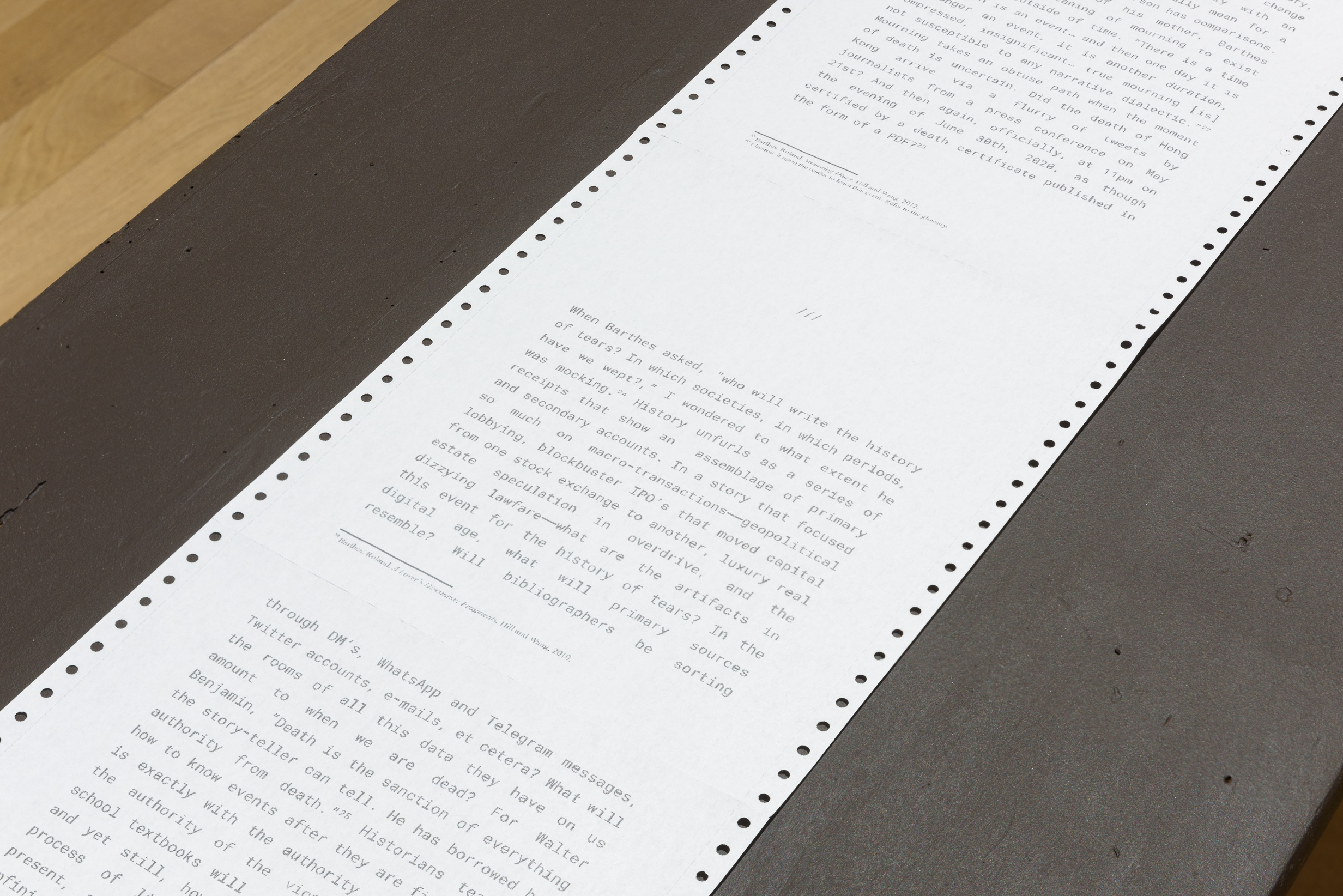 A photograph of a long sheet of dot matrix paper with text on a black table.
