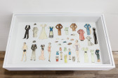 A vitrine displaying a nuclear family of paper dolls with their various options of clothing.